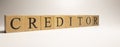 The name Creditor was created from wooden letter cubes. Economics and finance.