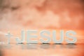 Name JESUS made with cement letters on orange light marble background. Copy space. Biblical, spiritual or christian