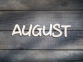 The name of the month is composed of light wooden letters on dark wood. The month of August.