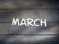 The name of the month is composed of light wooden letters on dark wood. The month of March.