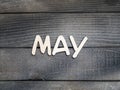 The name of the month is composed of light wooden letters on dark wood. The month of May.