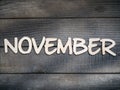 The name of the month is composed of light wooden letters on dark wood. The month of November.