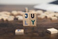 The name of the month July written on wooden cubes od the tabletop of th computer desk