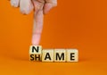 Name or shame symbol. Businessman turns the wooden cube and changes the concept word Shame to Name. Beautiful orange table orange