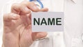 NAME word on the card in a man's hand on the background of a white shirt Royalty Free Stock Photo