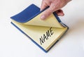 NAME word on paper of notebook opened by male hand