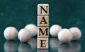 NAME - word on wooden cubes on a green background with wooden balls