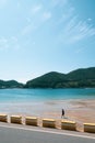 Namhae,South Korea-November 2020: Man walking at the sandy beach with blue clear water with mountain view at Namhae, South Korea