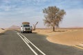 Namib Desert, Namibia, June 17, 2019: An SUV equipped for travel drives on a sandy paved road through the desert