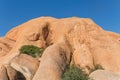 Namibia - Spitzkoppe - Smooth rounded granite rock formations and boulders with green bushes under clear blue sky Royalty Free Stock Photo