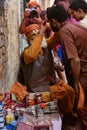 Elderly man paints symbols using gold paint onto the forehead of