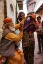 Elderly man paints symbols using gold paint onto the forehead of