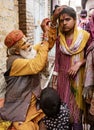 Elderly man paints symbols using gold paint onto the forehead of a woman