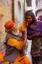 Elderly man paints symbols using gold paint onto the forehead of