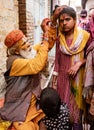 Elderly man paints symbols using gold paint onto the forehead of