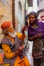 Elderly man paints symbols using gold paint onto the forehead of