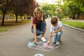 Nanny with cute little boy drawing house with chalks on Royalty Free Stock Photo