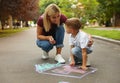 Nanny with cute little boy drawing house with chalks Royalty Free Stock Photo