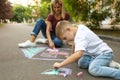 Nanny with cute little boy drawing house with chalks Royalty Free Stock Photo