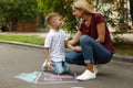 Nanny with cute little boy drawing house with chalks Royalty Free Stock Photo