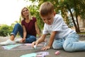 Nanny with cute little boy drawing house with chalks Royalty Free Stock Photo