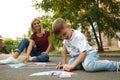 Nanny with cute little boy drawing house with chalks Royalty Free Stock Photo