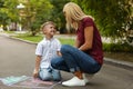 Nanny with cute little boy drawing house with chalks Royalty Free Stock Photo