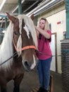 A woman combs a horse's mane at the stable in the Ethno-cultural tourist complex 