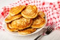Napkin, heap of cottage cheese pancakes in plate, fork on wooden table