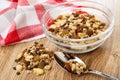 Napkin, heap of muesli, granola with banana and chocolate in bowl, muesli in spoon on wooden table