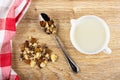 Napkin, heap of muesli, granola with banana and chocolate in spoon, pitcher with yogurt on table. Top view