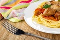 Napkin, plate with pieces of fried pork meat with lecho and spaghetti, fork on table