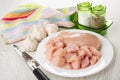 Napkin, salt and pepper, garlic, plate with raw chicken breast, knife on wooden table