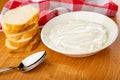 Napkin, slices of bread, spoon, soft cottage cheese in white bowl on wooden table