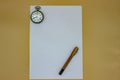 On a white sheet, an old gold fountain pen and an old pocket watch. The pen and the clock date back to the early 1900s, in fact yo