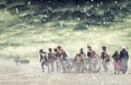 Napoleonic soldiers and women marching in falling snow and pulling a cannon in plain land, countryside with stormy clouds. Soldier