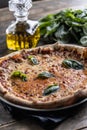 Napoli pizza with tomato sauce and mozzarella, fresh basil and a carafe of olive oil in the background