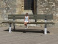 Unidentified elegant lady in summer clothes seated on a huge bench