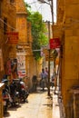Jaisalmer, India - August 20, 2009: narrow alley with shops, motorbikes and a cow in jaisalmer, Rajasthan, India