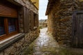 Narrow alley between stone houses with light in the background and reflections on the ground wet from the rain
