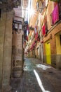 Narrow alleys of Toledo with shade cover, decorated balconies and sunbeams