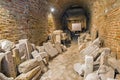 Narrow archway in a cellar filled with fragmented marble sculptures or decorative elements