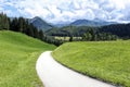 Narrow asphalt road to the valley in front of apline scenery Royalty Free Stock Photo