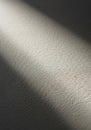 A narrow beam of light casts a diagonal shadow across a textured surface. The Royalty Free Stock Photo