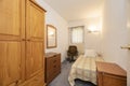 A narrow bedroom with a youthful bed and mismatched wooden furniture and a varnished pine wardrobe Royalty Free Stock Photo