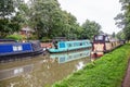 Narrow boats moored to bank of canal on sunny day with reflections in water near Oxford England Royalty Free Stock Photo