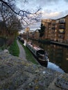 Narrow boats stationed along Regents Canal river and modern apartment flats alongside the river.