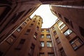 Narrow buildings well in Saint-Petersburg with the sky above the roofs. Below view.