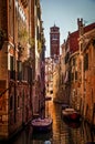 Narrow canal with boats and houses in the quiet backstreets of Venice with a view of a chruch tower. Beautiful pleasant warm