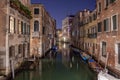Narrow canal with boats and vintage houses at dusk. Venice city at night Royalty Free Stock Photo